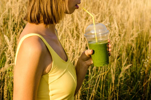 Energía verde y licuado nutricional bebida cóctel útil en la mano de una joven en el fondo borrosa naturaleza — Foto de Stock