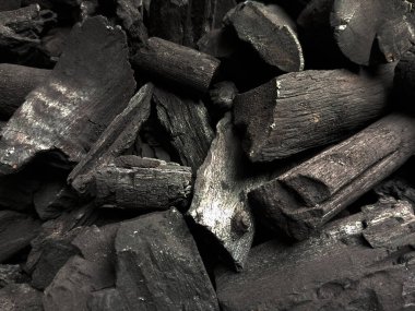 Siyah kömür parçalarına yakından bak. Kömür, tüm su ve uçucu bileşenleri yok etmek için çok az oksijenle odun ısıtılarak üretilir. Kömür arkaplanının tamamı.