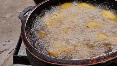 Koyu ya da siyah benekli eski metal tencerelerde kızartılmış muz manzarası. Kömür tenceresinde kızgın yağda kızartılmış muz. Kömür kabının içinde turuncu kömür alevi.