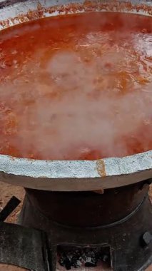 Kırmızı domates yahnisini büyük metal bir tencerede hazırlıyorum. Sıcak yağda pişirirken çıkan buharlı domates yahnisi. Gıda süreci.