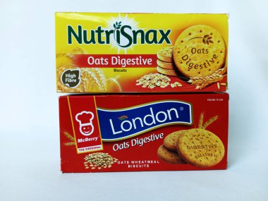Kumasi, Gana - 9 Aralık 2025: İki farklı marka yulaflı bisküvi. McBerry 'den Red London bisküvisi. Orijinal ve sarı NutriSnax. Yazan Gana Limited. Beyaz arka planda paket buğday ezmeli bisküvi. Çift p 'nin ön görünümü