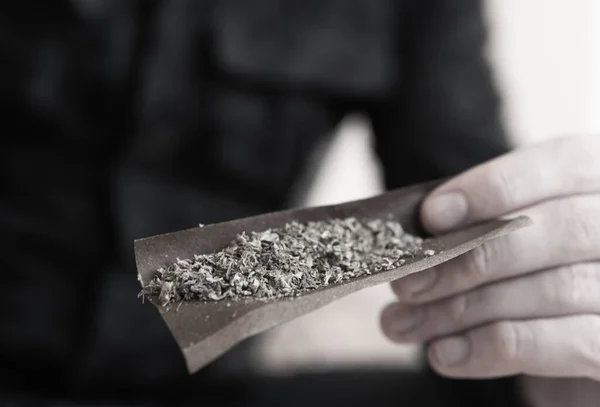 Тупой. Наркотическая концепция. Крупный план наркомана, освещающего марихуану Блант зажигалкой. — стоковое фото