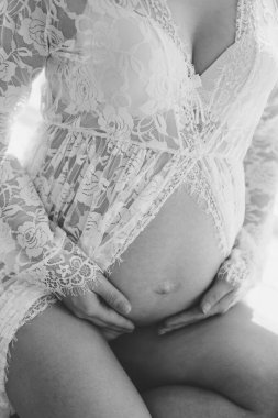 Hamile bir kadının elleriyle karnına dokunduğu, karnını tutan hamile bir kadın. Beyaz arka planda hamile bir kadının karnı, dokuz ay. Hamile kız..