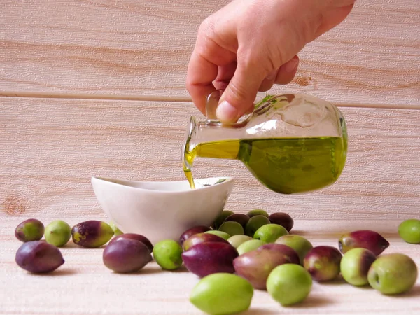 Yunan zeytinyağı. Yunanistan 'da doğal, çevre dostu zeytinyağı, masada taze yeşil ve siyah zeytinlerle çevrili küçük bir tabağa elle döküldü.