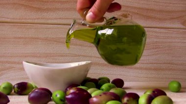 Yunan zeytinyağı. Yunanistan 'da doğal, çevre dostu zeytinyağı, masada taze yeşil ve siyah zeytinlerle çevrili küçük bir tabağa elle döküldü.