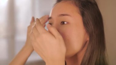 Güzellik derisi ve makyaj rutini yapan bir kadın, rimel, göz kalemi, dudak parlatıcısı, toner ve fondöten sürmüş. Güzellik dersleri, kozmetik ve kişisel bakım için mükemmel bir konsept.