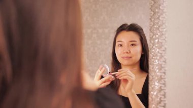 Güzellik derisi ve makyaj rutini yapan bir kadın, rimel, göz kalemi, dudak parlatıcısı, toner ve fondöten sürmüş. Güzellik dersleri, kozmetik ve kişisel bakım için mükemmel bir konsept.