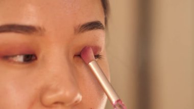 Güzellik derisi ve makyaj rutini yapan bir kadın, rimel, göz kalemi, dudak parlatıcısı, toner ve fondöten sürmüş. Güzellik dersleri, kozmetik ve kişisel bakım için mükemmel bir konsept.