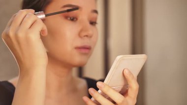 Güzellik derisi ve makyaj rutini yapan bir kadın, rimel, göz kalemi, dudak parlatıcısı, toner ve fondöten sürmüş. Güzellik dersleri, kozmetik ve kişisel bakım için mükemmel bir konsept.