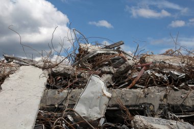 İnşaat enkazı, paslanmış metal çubuklar ve çatlamış beton levhalar. Ruh hali, yıkım ve yıkım izlenimi veriyor. Ama sahnede engebeli bir güzellik var. İzole edilmiş ortam, insan yapımı kaosun ve doğal güzelliğin etkileşimini vurguluyor..