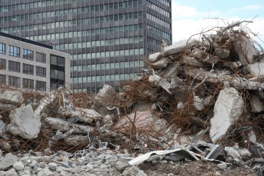 Moloz ve molozlardan oluşan bir arazinin hakim olduğu kentsel bir ortamda inşaat alanı. Bitmiş binaların siluetine karşı inşaat faaliyetlerinin yan yana getirilmesi, kentteki süregelen ilerleme ve yenilenmenin hikayesini anlatıyor..