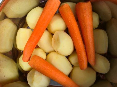 Close-up of peeled raw potatoes and carrots ready for cooking