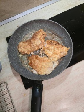 Top-down view of pork cutlets frying in oil on a non-stick pan