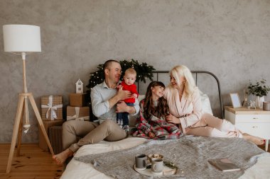 Noel ve tatiller için dekore edilmiş şık, modern bir yatak odasında iki çocuklu mutlu bir aile. Yeni yıl, Noel