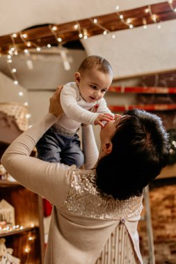 Küçük torunuyla kucağına aldığı ve oynadığı mutlu büyükannesi, süslü bir Noel ağacının yanında bir aile anını kutluyor, hem de sade bir tatil evinde. Yeni yıl, Noel