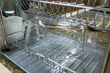 Temiz, büyük bir cam kase yakın çekim bir mutfak gümüş metal rafta baş aşağı kurumak, altında ıslak bir tepsi ve yakın küçük çatal bıçak