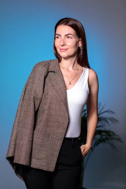 Omzuna montla poz veren kendine güvenen şık bir iş kadını. Mavi ve Cyan stüdyosunun arka planında, el ele.