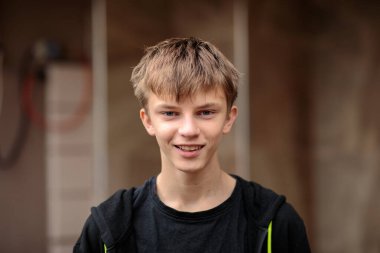 Siyahi kapüşonlu, ciddi, düşünceli bir gencin yakın plan portresi ya da gençlik öncesi bir çocuğun bulanık bir şehir geçmişine karşı düşünceli bir ifadeyle başka yere bakması..