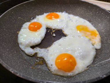Dört mükemmel pişmiş, güneşli tarafı tepeden aşağı, sağlıklı bir kahvaltı için granit etkisi olmayan tavada kızaran yumurtalar.