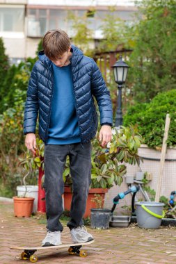 Genç bir çocuk dışarıda kaykayla bir numara yapıyor ya da zıplıyor, dinamik hareketler ve hareketler sergiliyor.