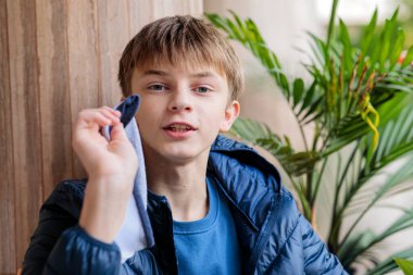 Genç bir çocuğun yakın plan portresi. Spor yaptıktan sonra yüzünü bir bezle siliyor, verandada dinleniyor.