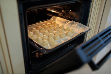 Fırının içinde duran ve pişirme işleminin başlamasına hazır, sıralanmış çiğ İspanyol solenki tuzlu peynirli hamur işleri ile pişirme tepsisi.