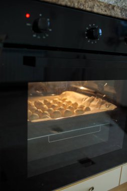 Bulgar solenki tuzlu peynirli hamur işleri, cam kapıdan görülebilen ve yukarıda fırın kontrolleri olan modern siyah elektrikli fırının içinde pişiyor.