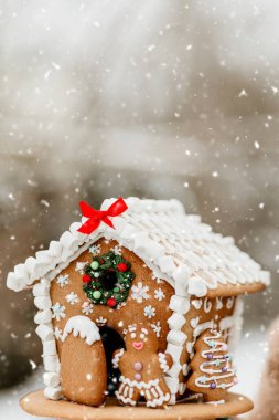 Süslü, zencefilli, küçük bir kurabiye adam ve şekerli karla süslenmiş bir evin ayrıntıları. Noel kutlaması ve geleneksel kış yemekleri konsepti.