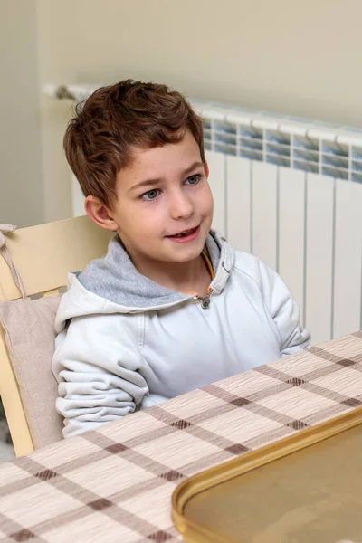 Küçük mutlu çocuk, tatil pişirme atölyesi sırasında mutfak masasında oturuyor, neşeli çocuk evde yaratıcı noel etkinliğine katılıyor ve aile kutlamalarına katılıyor.