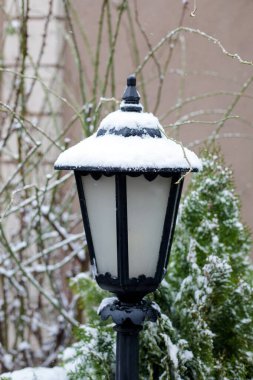 Klasik kara bahçe feneri kış karı yağışında taze karla kaplanmış, açık hava dekoratif sokak lambası yerleşim alanında, soğuk hava mevsimsel atmosfer