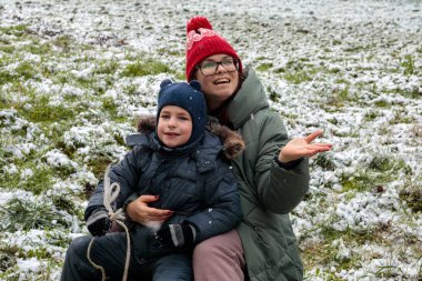 Mutlu anne ve oğul ilk kar yağışının keyfini çıkarıyorlar, sıcak aile anı, kış anneliği konsepti, duygusal bağ, ebeveynlik aşkı, mevsimlik yaşam tarzı ve anneler günü teması