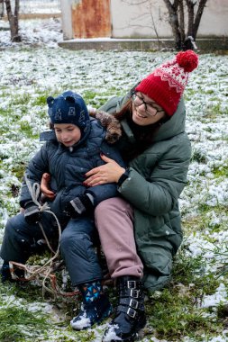 Mutlu anne ve oğul ilk kar yağışının keyfini çıkarıyorlar, sıcak aile anı, kış anneliği konsepti, duygusal bağ, ebeveynlik aşkı, mevsimlik yaşam tarzı ve anneler günü teması