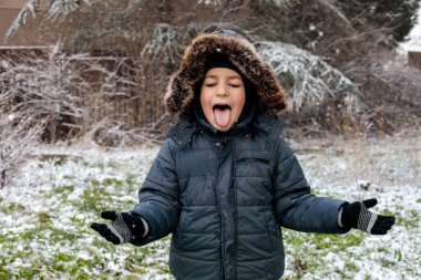 Oyuncu çocuk kışın ilk kar yağışında dışarıda eğleniyor. Kürk kapüşonlu ve eldivenli kalın bir ceket giyiyor. Dilini çıkarıp kar tanelerini yakalıyor.