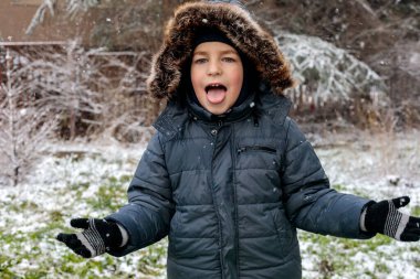 Oyuncu çocuk kışın ilk kar yağışında dışarıda eğleniyor. Kürk kapüşonlu ve eldivenli kalın bir ceket giyiyor. Dilini çıkarıp kar tanelerini yakalıyor.
