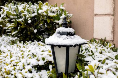 Klasik kara bahçe feneri kış karı yağışında taze karla kaplanmış, açık hava dekoratif sokak lambası yerleşim alanında, soğuk hava mevsimsel atmosfer