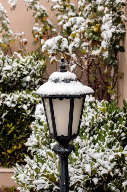 Klasik kara bahçe feneri kış karı yağışında taze karla kaplanmış, açık hava dekoratif sokak lambası yerleşim alanında, soğuk hava mevsimsel atmosfer
