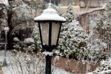 Klasik kara bahçe feneri kış karı yağışında taze karla kaplanmış, açık hava dekoratif sokak lambası yerleşim alanında, soğuk hava mevsimsel atmosfer