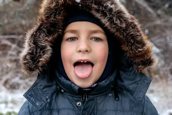 Oyuncu çocuk kışın ilk kar yağışında dışarıda eğleniyor. Kürk kapüşonlu ve eldivenli kalın bir ceket giyiyor. Dilini çıkarıp kar tanelerini yakalıyor.