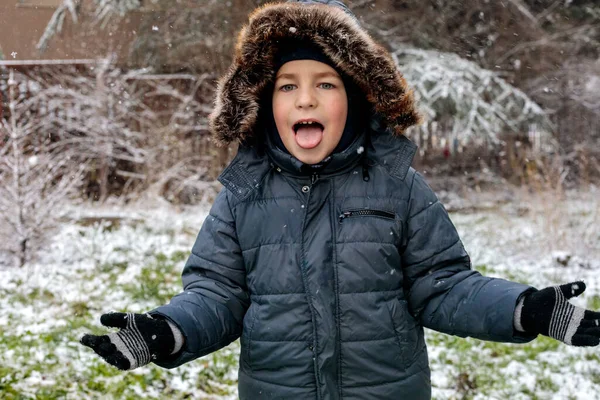 Oyuncu çocuk kışın ilk kar yağışında dışarıda eğleniyor. Kürk kapüşonlu ve eldivenli kalın bir ceket giyiyor. Dilini çıkarıp kar tanelerini yakalıyor.