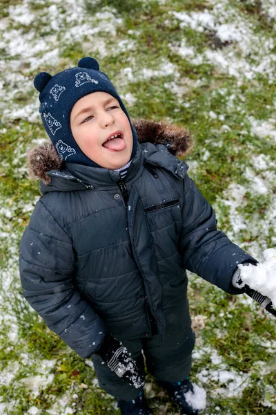 Oyuncu çocuk kışın ilk kar yağışında dışarıda eğleniyor. Kürk kapüşonlu ve eldivenli kalın bir ceket giyiyor. Dilini çıkarıp kar tanelerini yakalıyor.