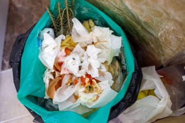 Çöp tenekesinde yiyecek atıkları, ev çöpleri ve organik artıklar.
