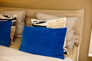 Mavi aksanlı yastıklı, katmanlı yatak odası.