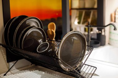 Mutfak lavabosunun yanında siyah seramik tabaklar kuruyor.