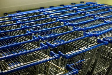 Bir süpermarketin içine düzgünce istiflenmiş mavi saplı boş alışveriş arabaları, temiz perakende iç mekan düzeni, hazırlık, tüketici hizmeti ve modern alışveriş kolaylığı