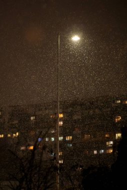 Geceleri evlerin üzerine düşen karları aydınlatan sokak lambaları sıcak soğuk hava ve kentsel akşam manzarası ile kasvetli bir kış şehri atmosferi yaratır.