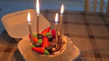 Beyaz şekerli doğum günü pastası ve birkaç mum, sıcak bir parıltı, kutlama atmosferinin şenlikli ve samimi atmosferini yansıtıyor.