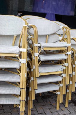 Dışarıdaki sandalyeler bambu tarzı çerçeve ve aydınlık kumaş koltuklar ile döşenmiş, inşaat cephesinin yanındaki asfaltlı yüzeye yerleştirilmiş.