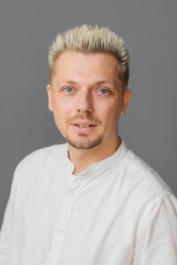 Tarafsız gri arka planda kameraya bakan kendinden emin bir gencin portresi, doğal ifade, modern tarz, sakin kişilik ve profesyonel yaşam tarzı konsepti