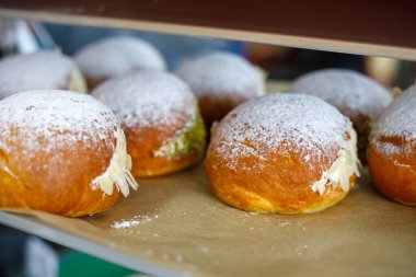 Tepside pudra şekerli ve kremalı taze çörekler, yumuşak doku ve sıcak tonlarda..