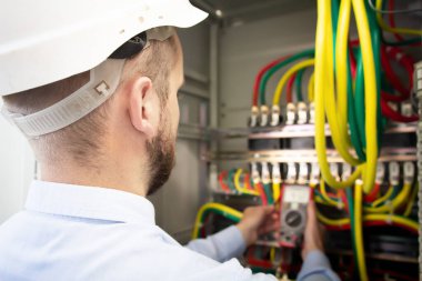 Görevli sigorta kutusunu ayarlıyor. Elektrik mühendisi elektrik kabinesindeki voltajı ölçtü.